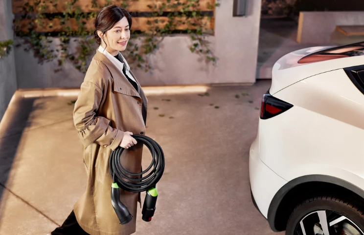 A woman holds a Habu next to a Tesla